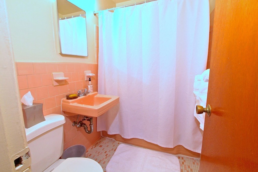 a bathroom with pink tiles and a white shower curtain