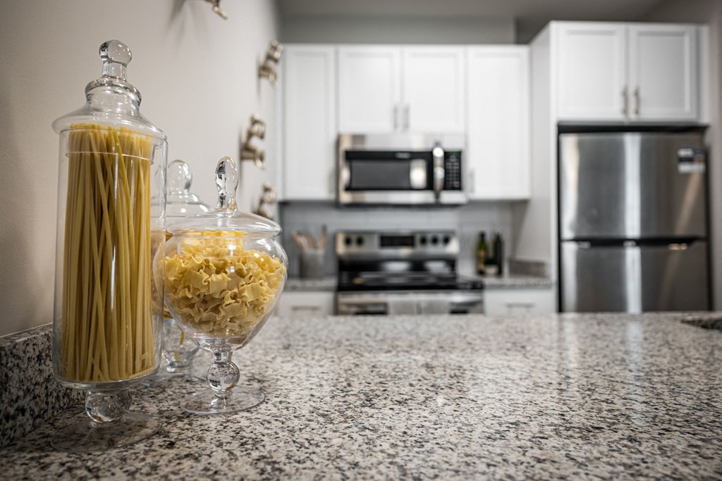 a kitchen counter with a jar of pasta and a glass vase of pasta