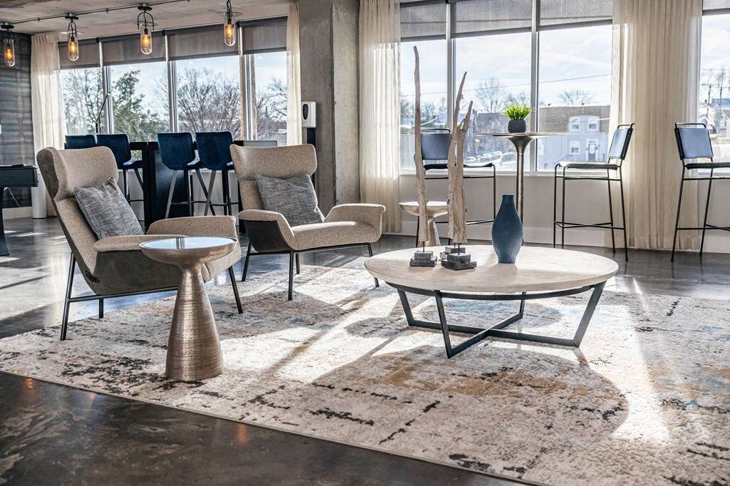 a living room with chairs and tables and a large rug