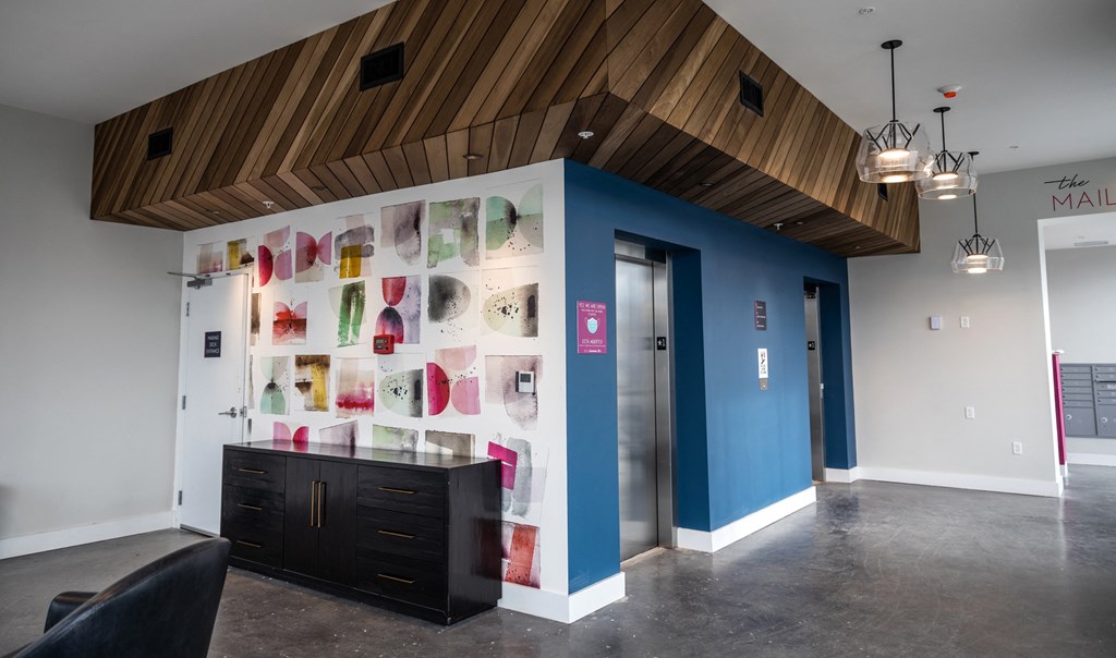a lobby with a glass display case with colorful purses on the wall