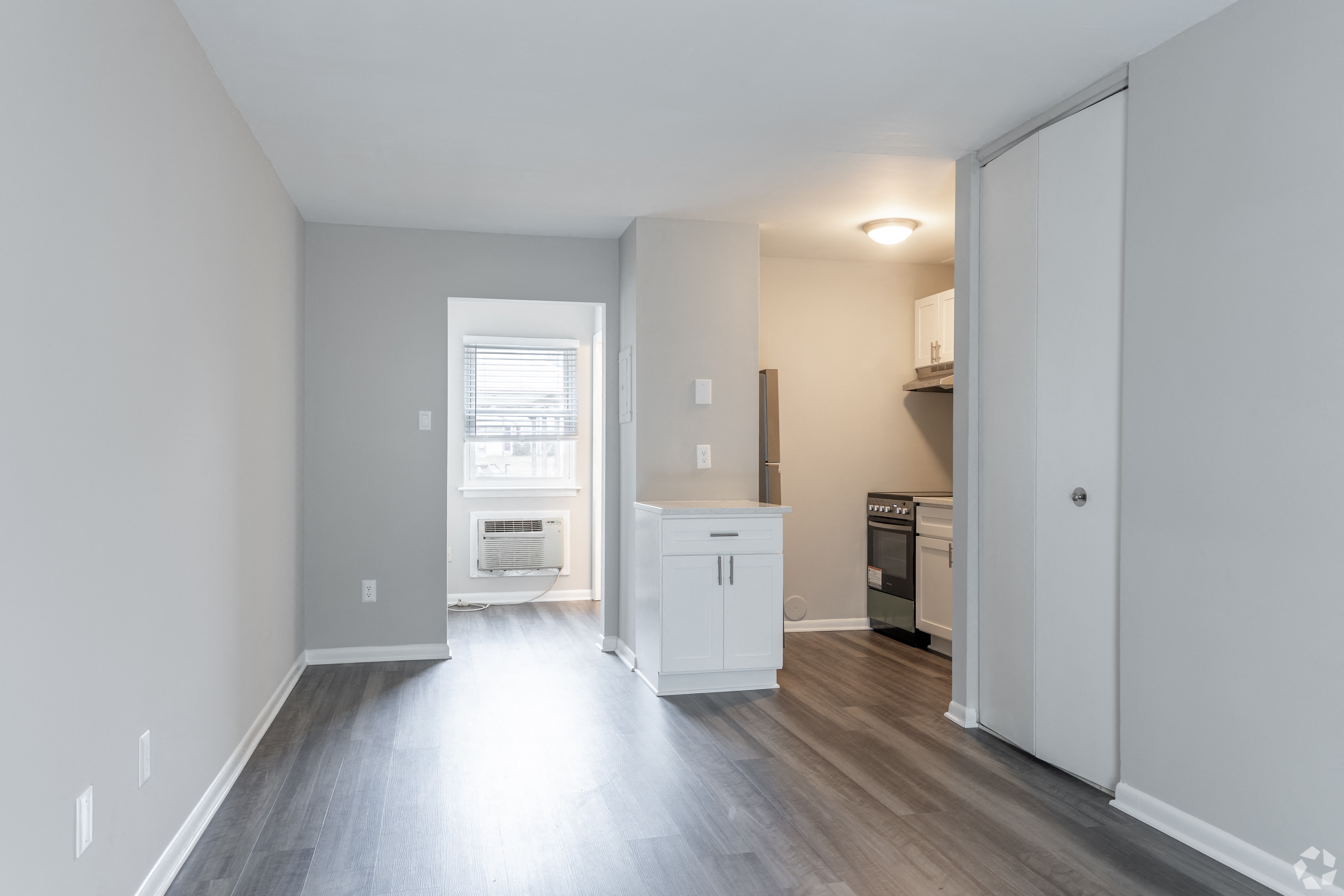 an empty living room and kitchen with wood flooring and a window