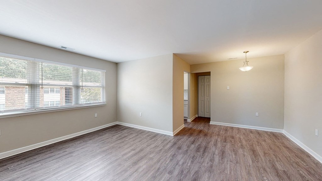 an empty living room with a large window and wood flooring