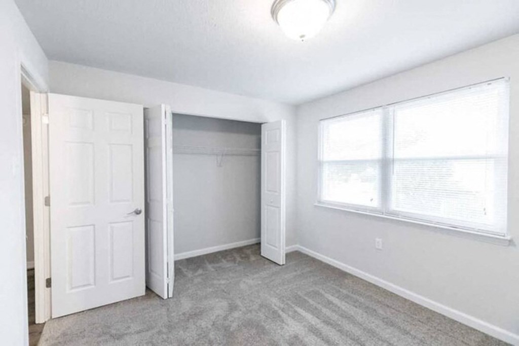 an empty bedroom with a closet and a window