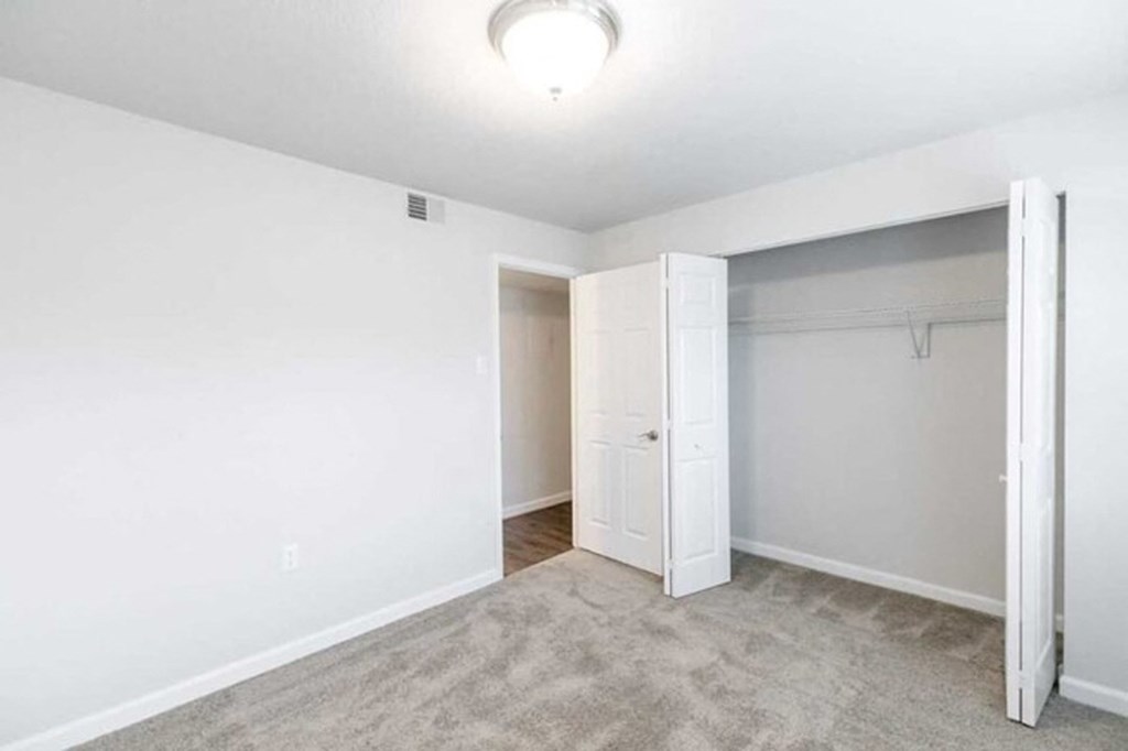 an empty bedroom with a closet and a white closet door