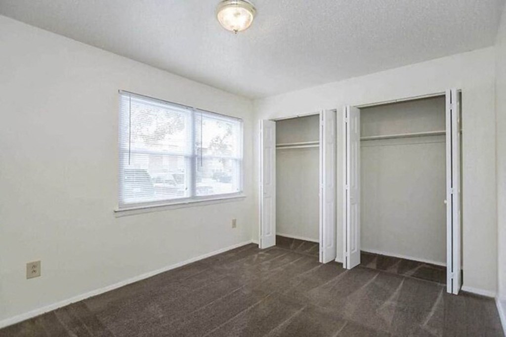 an empty living room with a large window and two doors