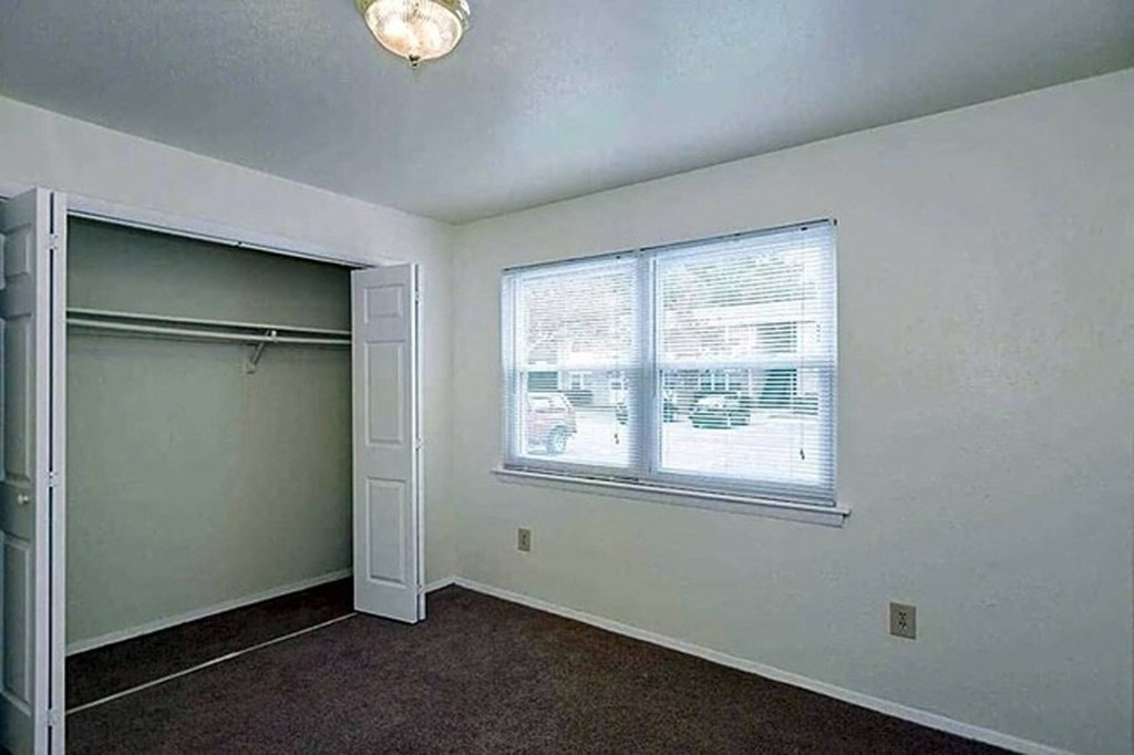 an empty room with a window and a closet