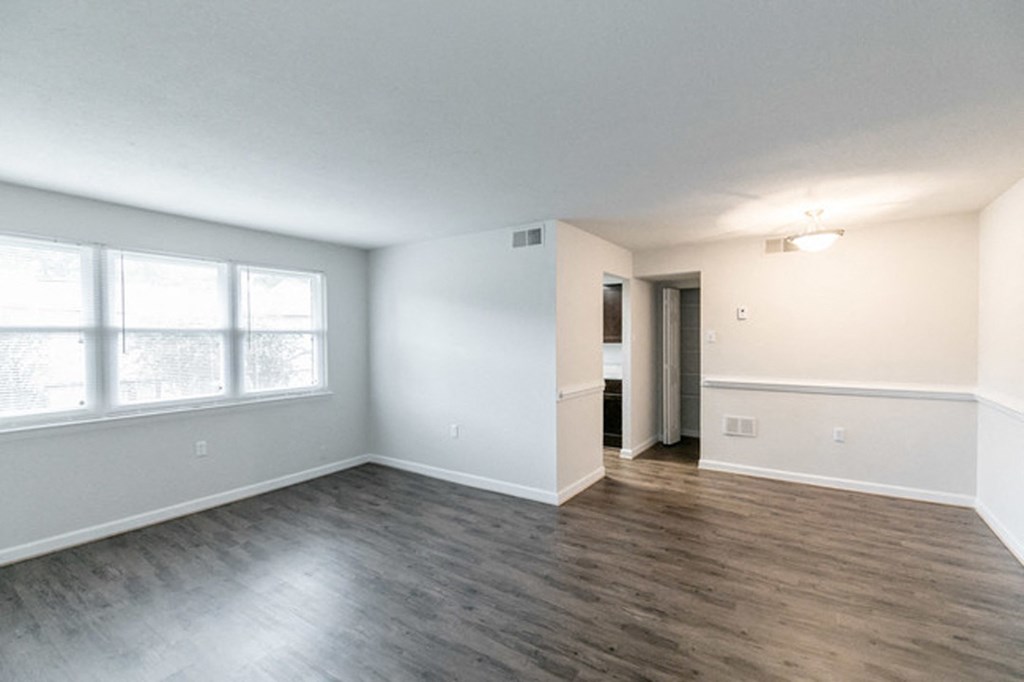 an empty living room with wood flooring and a large window