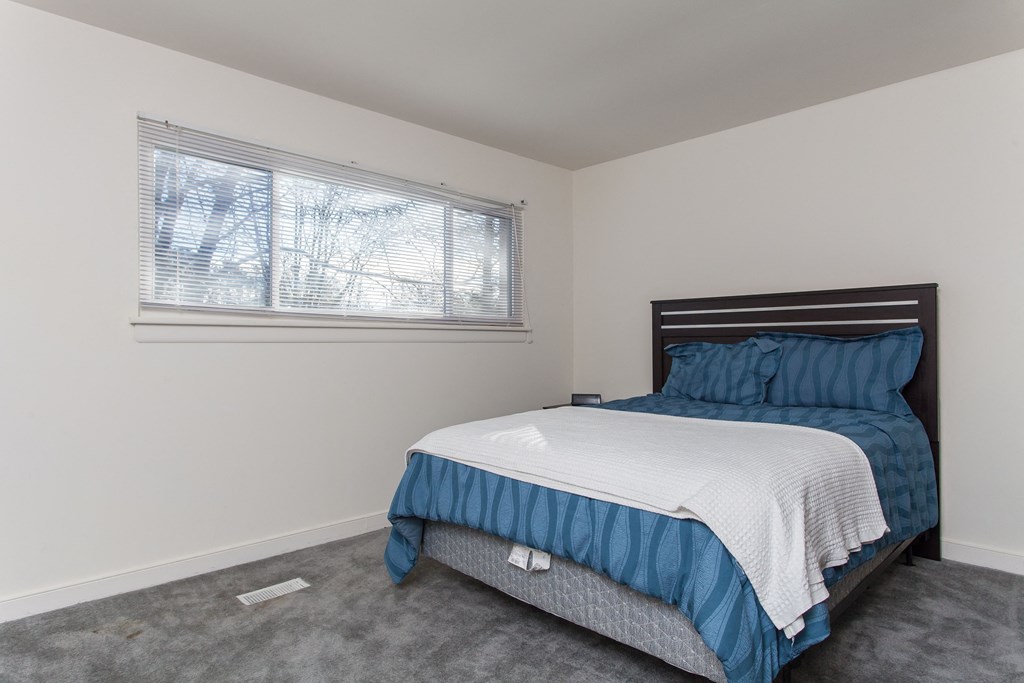 an empty bedroom with a bed and a window