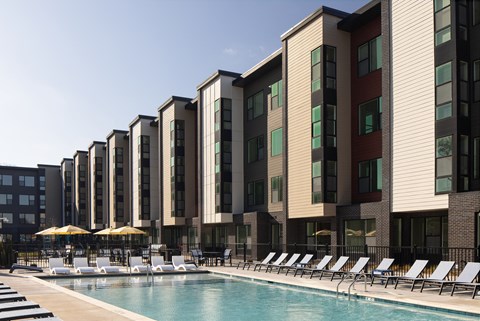 A row of modern apartment buildings with a pool in front.