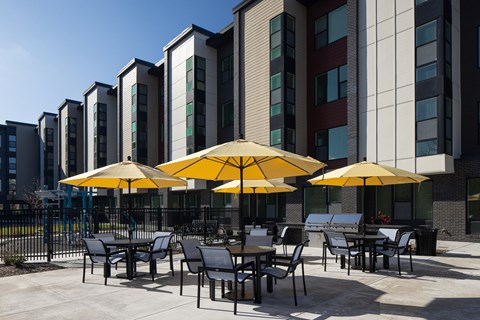 A patio with tables and chairs and umbrellas in front of a building.