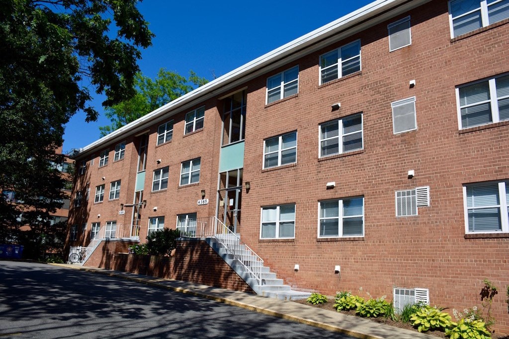 a large brick apartment building with stairs and a street in front of it