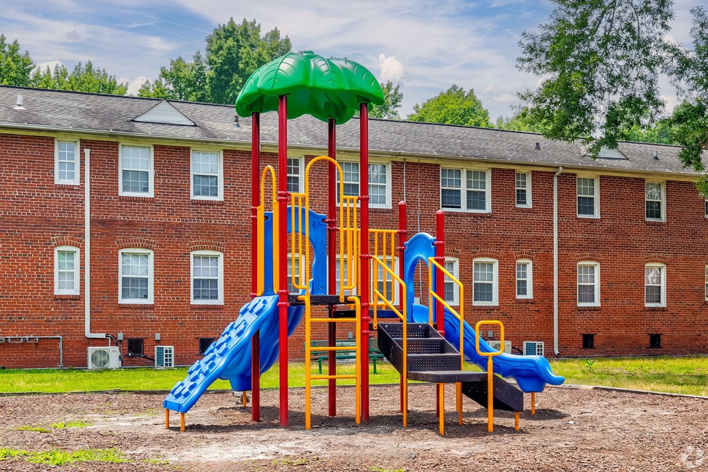 a playground in a yard in front of a brick building