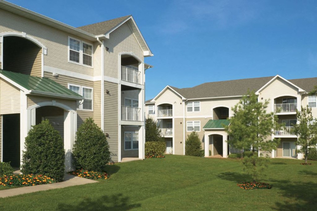 an exterior view of apartments with grass and trees