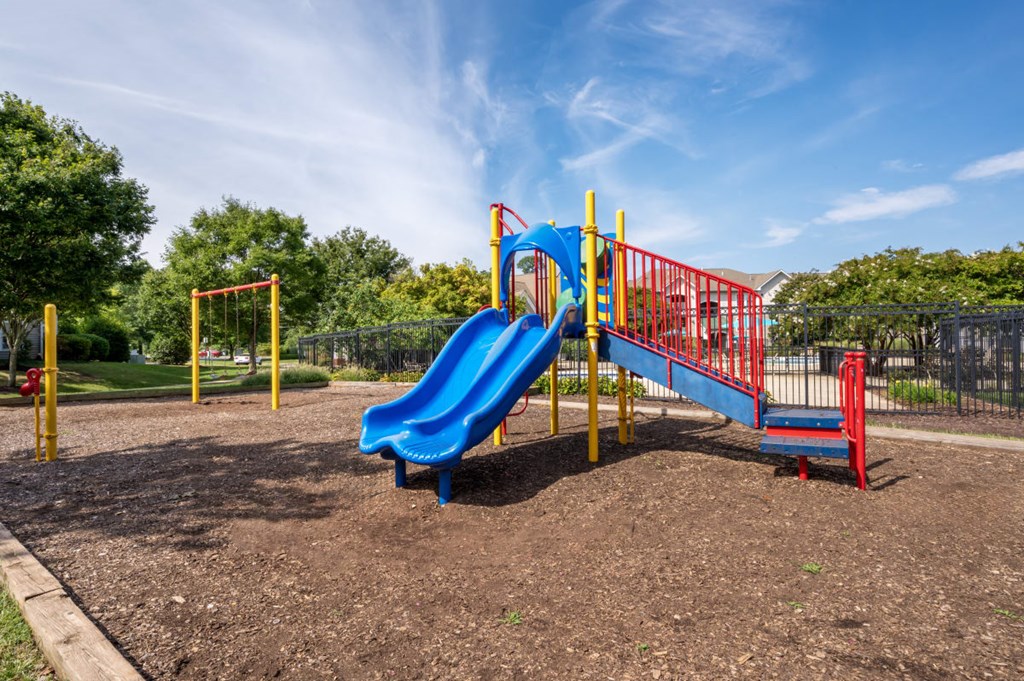 a playground with a blue slide and a red swing set