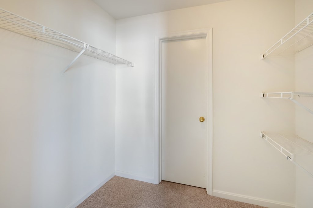 a walk in closet with white walls and a white door