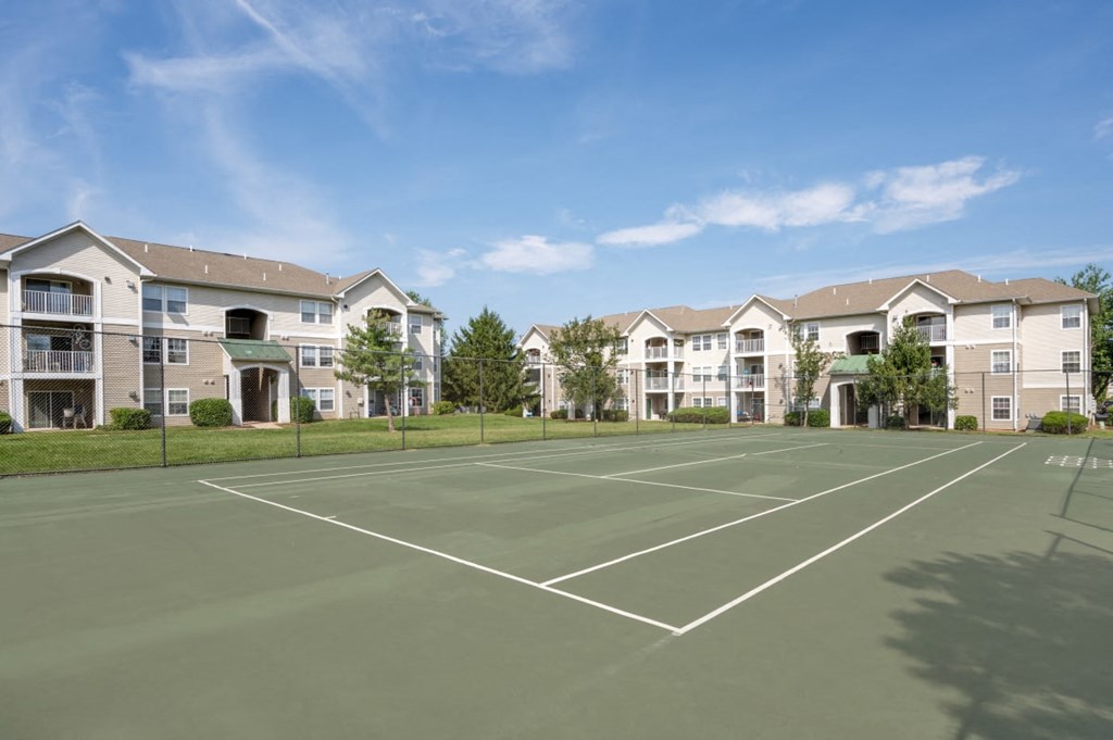 an empty tennis court with apartments in the background