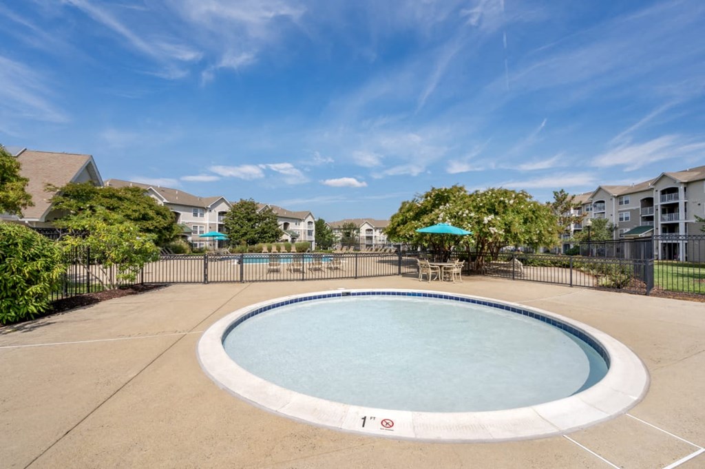 an oval swimming pool with a fence and apartments in the background