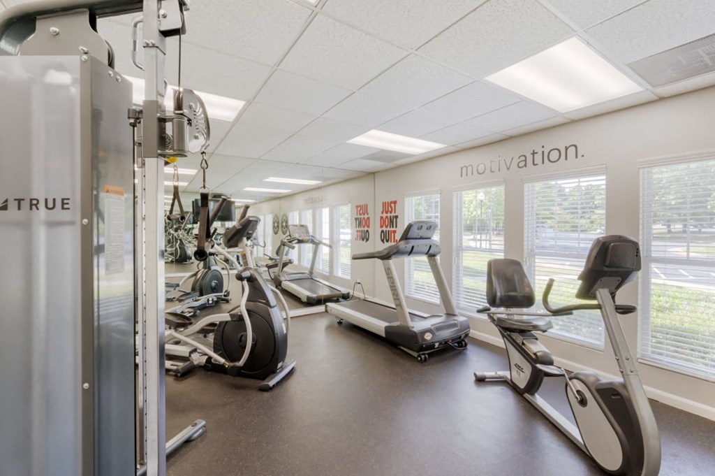 a gym with cardio equipment and windows in a building