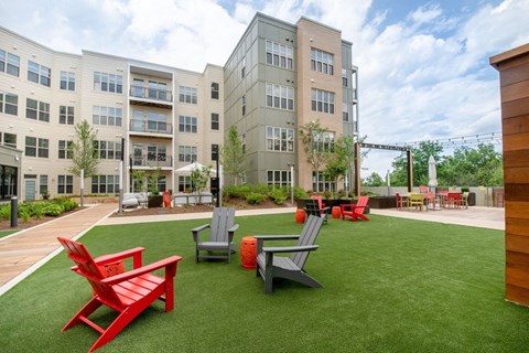 a courtyard with red chairs and lawn chairs in front of an apartment building