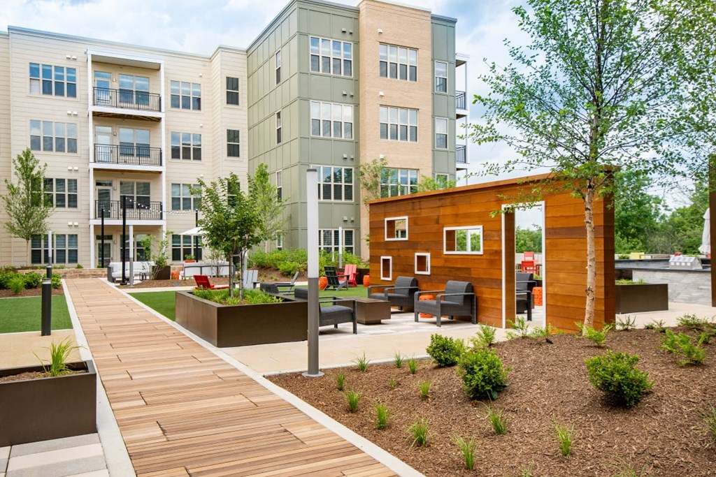 a courtyard with a wooden walkway and benches in front of an apartment building