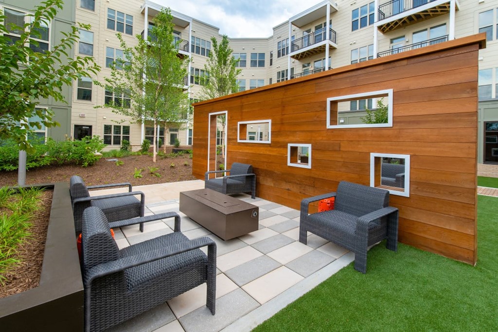 a backyard patio with chairs and a wooden shed