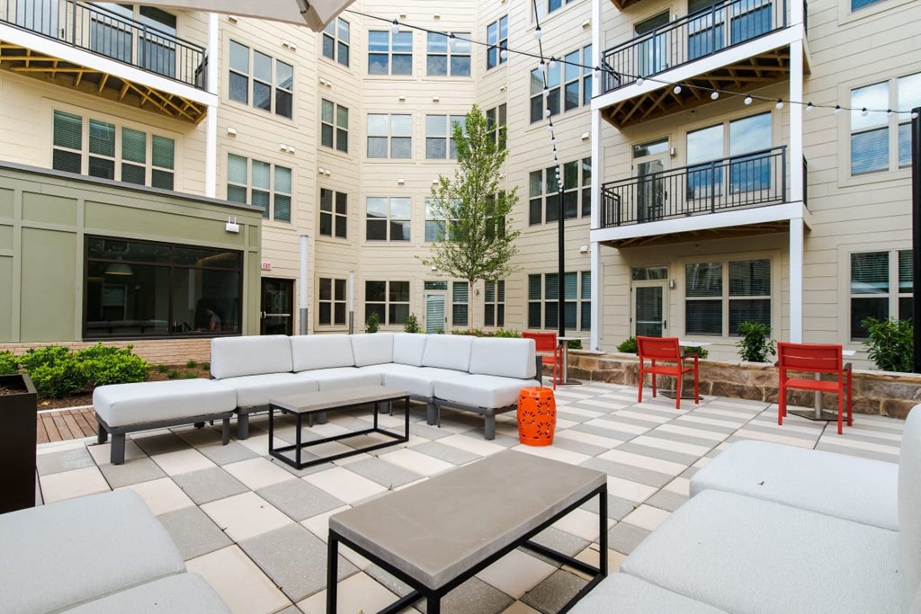 an outdoor patio with couches and tables in front of an apartment building
