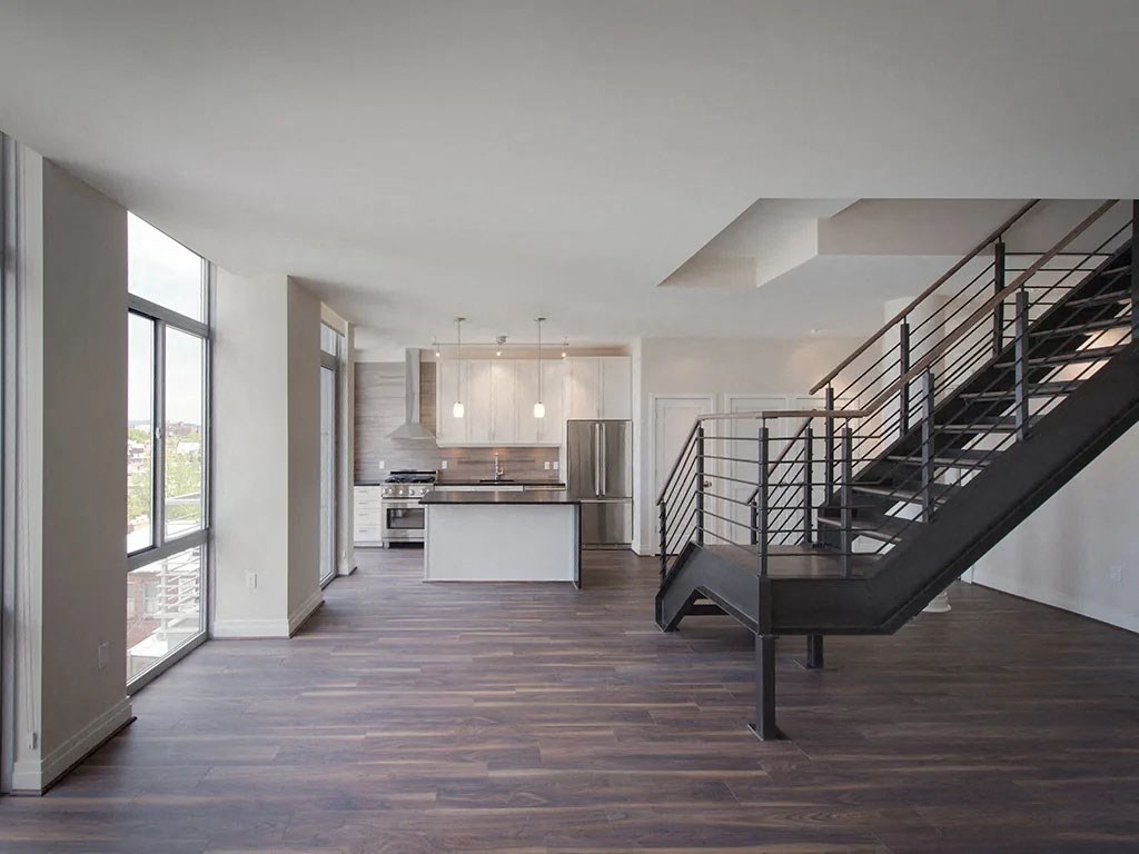 a large living room with a staircase and a kitchen