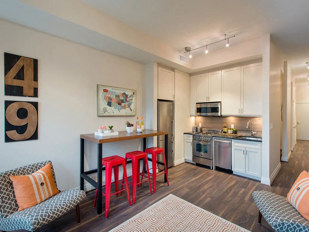 a living area with a kitchen and a bar with red stools