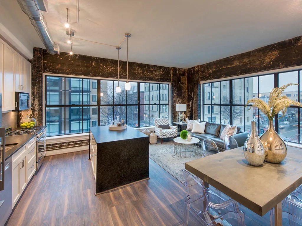 a kitchen and living room with large windows and a table