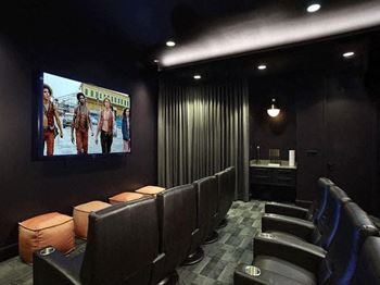 a theater room with leather chairs and a tv
