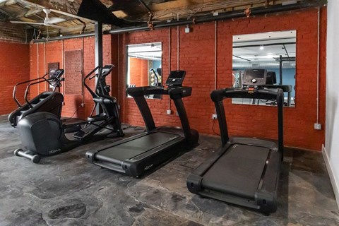 Three treadmills are lined up in a gym.