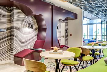 a seating area with tables and chairs in front of a wall with a wavy design