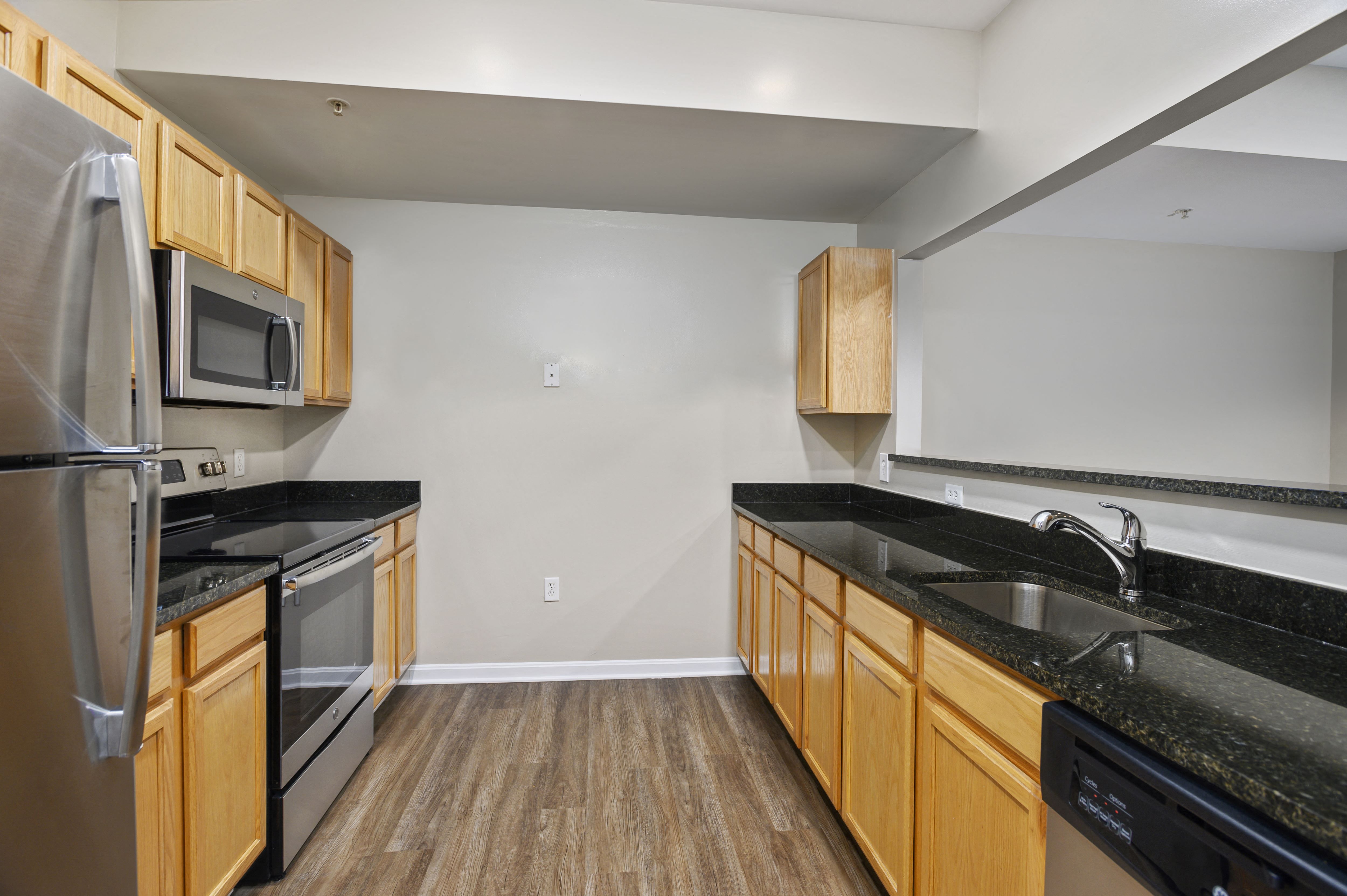 A kitchen with wooden cabinets and black countertops.