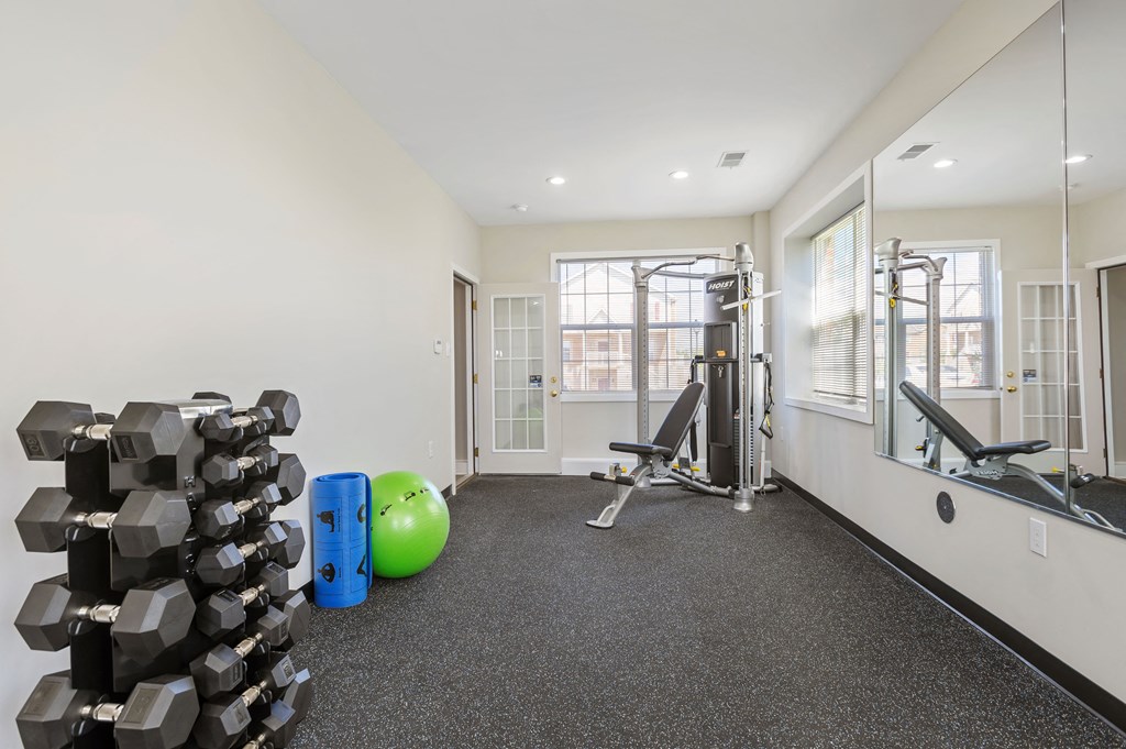 A gym with a variety of equipment including dumbbells, a medicine ball, and a squat rack.