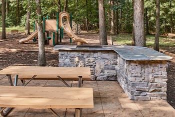 a stone bar and picnic tables in front of playground equipment