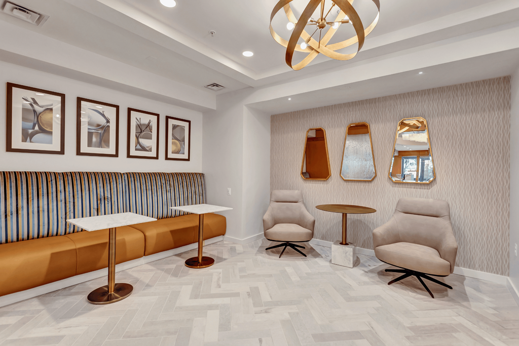 A room with a bench, chairs, and pictures on the wall.