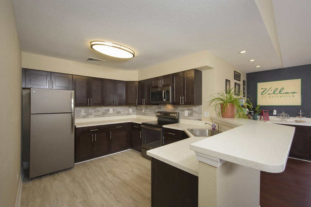 a large kitchen with stainless steel appliances and white counter tops