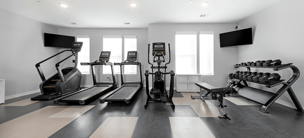 a gym with treadmills and televisions on the wall