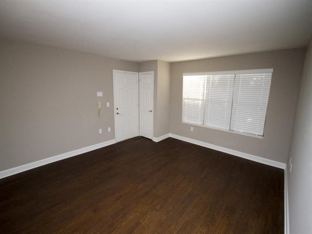an empty room with a door and two windows