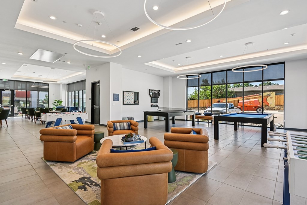 A modern living room with a large window overlooking a parking lot.