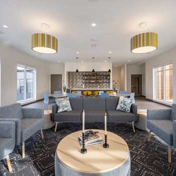 Community room at Aura at Innovation Square apartments with couches and chairs and a table