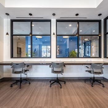a large desk with chairs in a room with windows at Aura at Innovation Square apartments