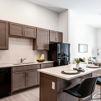 a kitchen with wooden cabinets and a quartz island with a table and chairs
