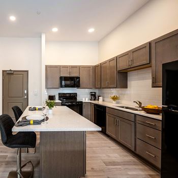 a kitchen with dark wood cabinets and a quartz counter top at Aura at Innovation Square apartments
