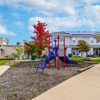a playground with a blue and red swing set in front of houses
