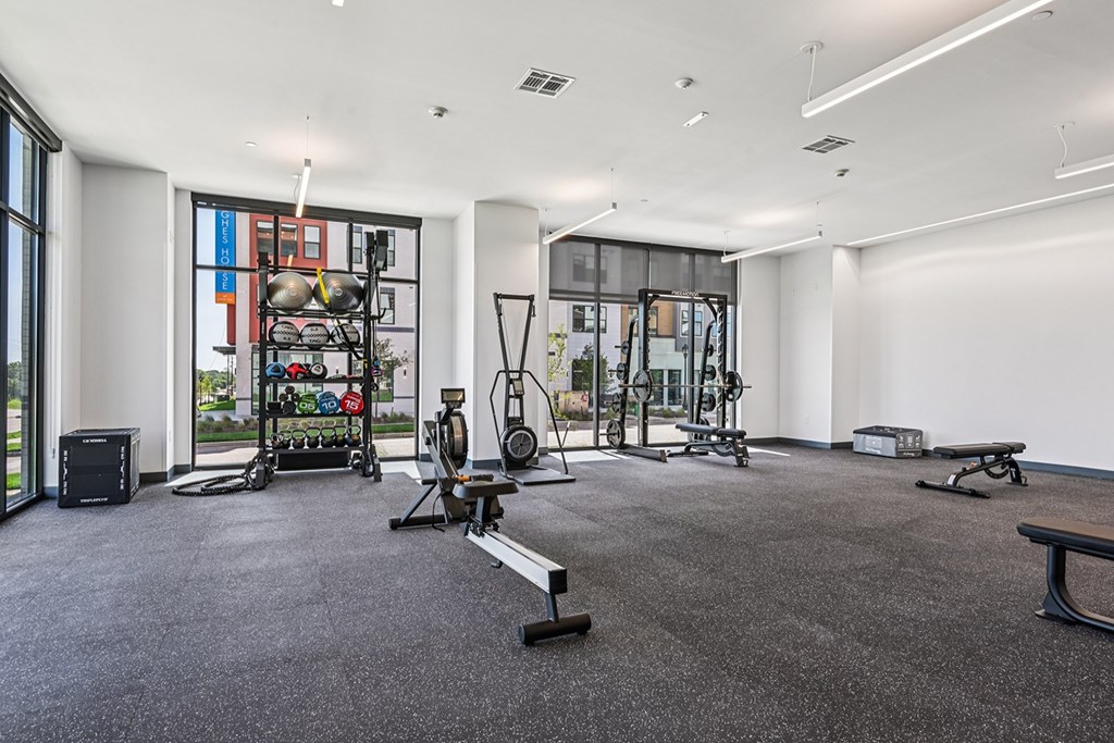 A gym with a variety of equipment including a treadmill, weights, and a bench.
