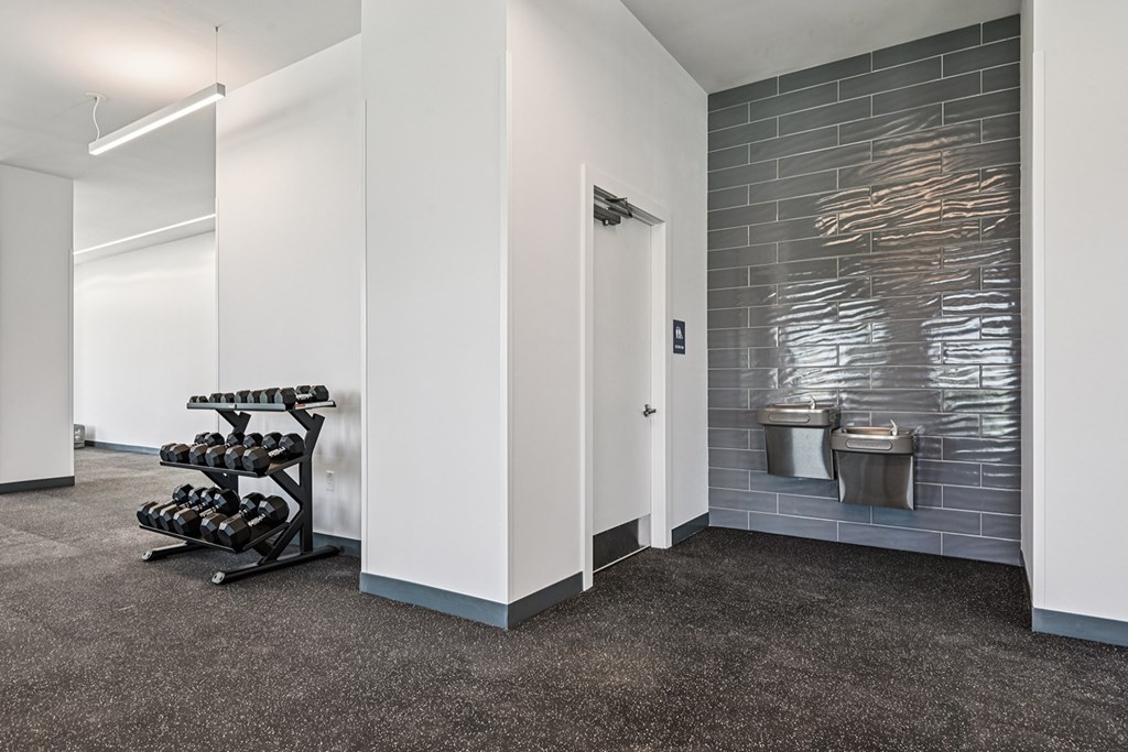 A gym room with a weight rack and a mirror.