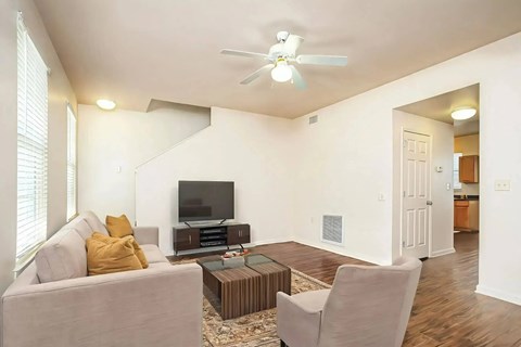 A living room with a grey couch, a brown coffee table, and a white ceiling fan.