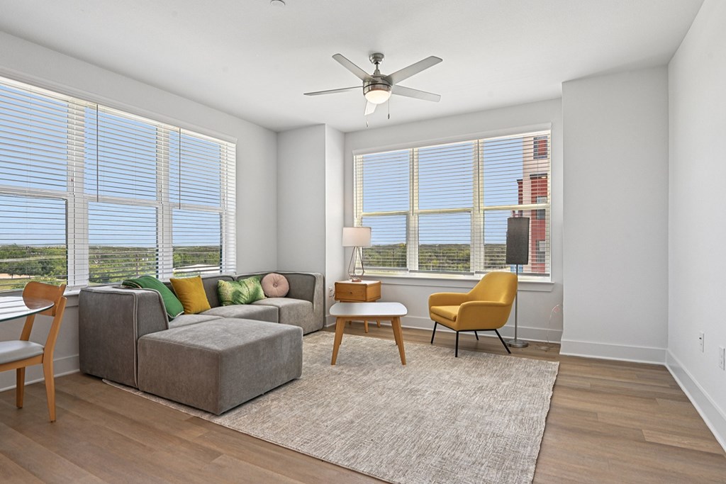 A living room with a grey couch, a yellow chair, and a ceiling fan.