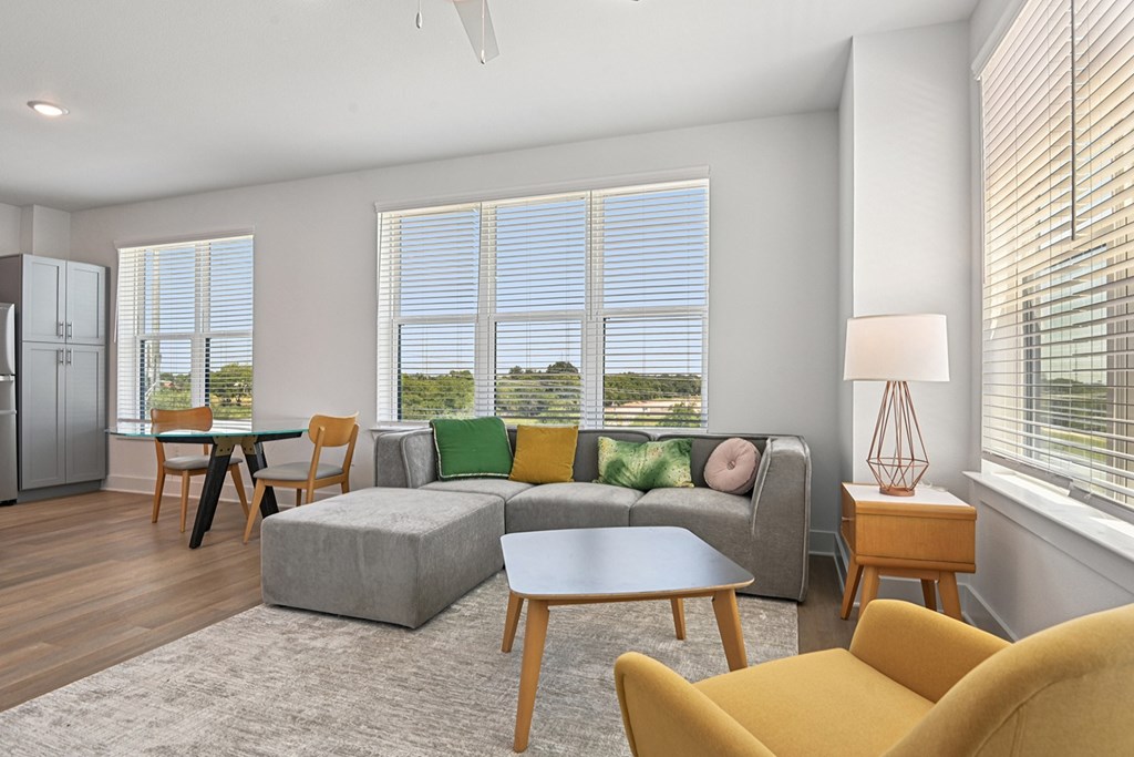 A living room with a grey couch, yellow chairs, and a table.